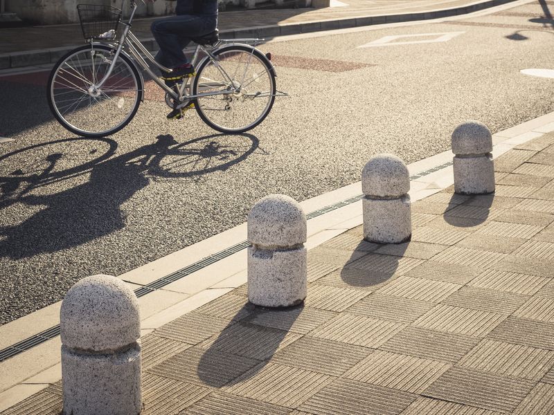 concrete-bollards-on-walkway-city-people-cycling-on-street-urban-min