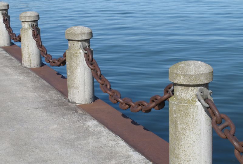 concrete-bollards-posts-and-chain-on-a-pier-min